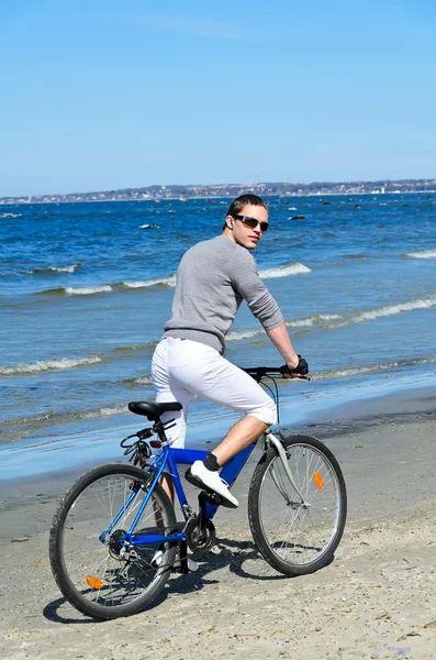 Retrato de belo macho andando de bicicleta junto ao mar — Fotografia de Stock