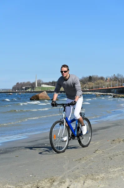 Porträt eines hübschen Mannes, der am Meer Fahrrad fährt — Stockfoto