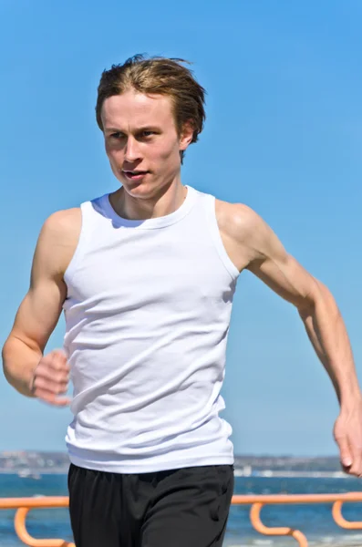 Atlético jovem do sexo masculino correndo na costa — Fotografia de Stock