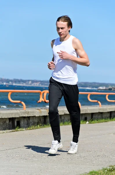 Atlético jovem do sexo masculino correndo na costa — Fotografia de Stock