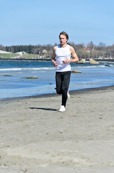 Молодой спортсмен бегает по пляжу — стоковое фото