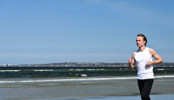 Αθλητική νεαρά αρσενικά που τρέχει στην παραλία — Φωτογραφία Αρχείου