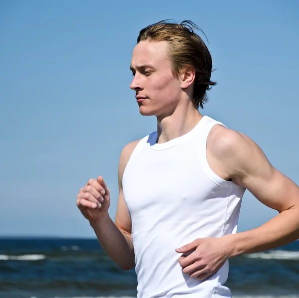 Atlético jovem do sexo masculino correndo na praia — Fotografia de Stock
