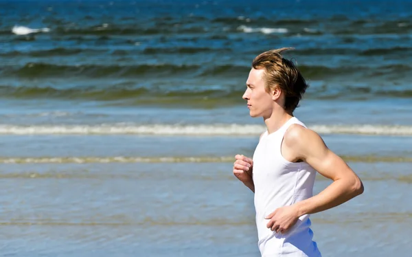 Atlético jovem do sexo masculino correndo na praia — Fotografia de Stock