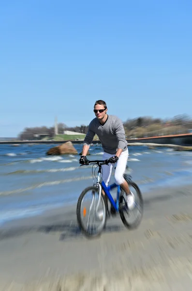 Motion blur: male riding a bicycle by the sea — Stock Photo, Image