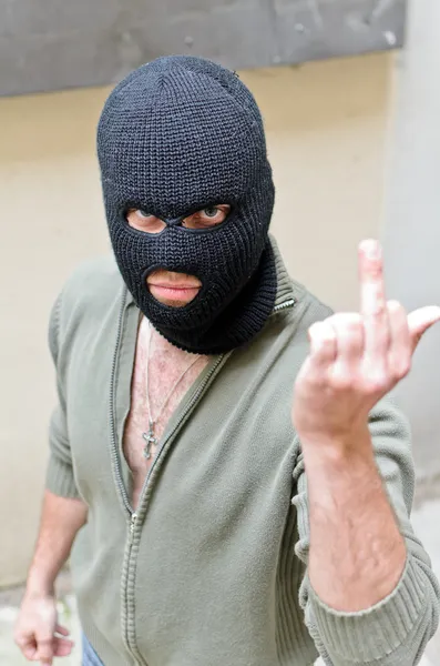 Inbreker dragen van een masker toont fuck gebaar. — Stockfoto
