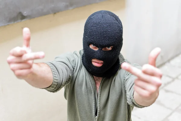 Inbreker dragen van een masker toont fuck gebaar. — Stockfoto