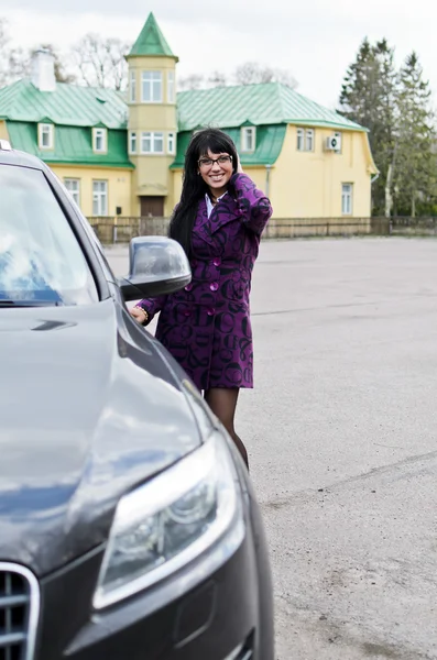 Vacker kvinna i en kappa sitter i en dyr bil — Stockfoto