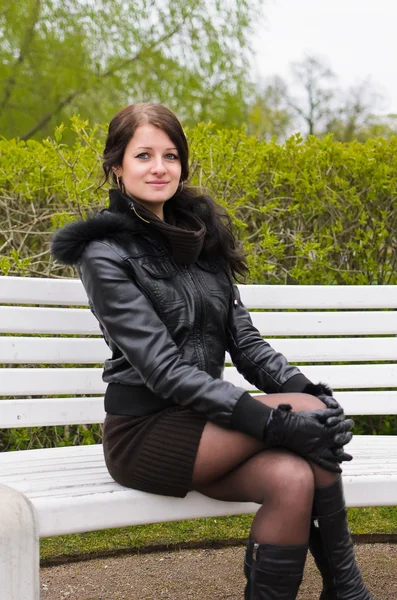 Atrakcyjna dziewczyna siedzi na ławce w parku — Zdjęcie stockowe
