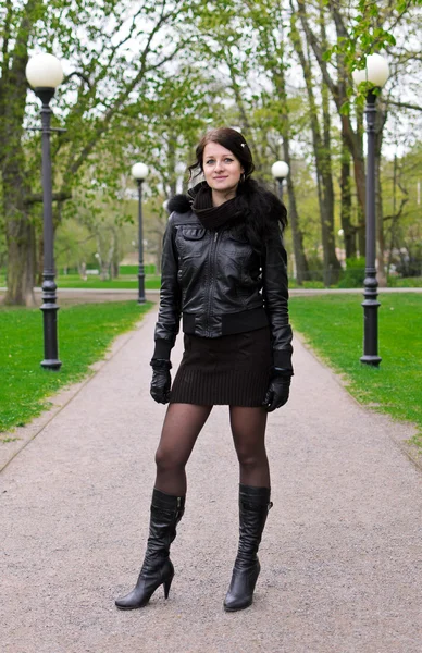 Ragazza attraente in una giacca sulla strada nel parco — Foto Stock