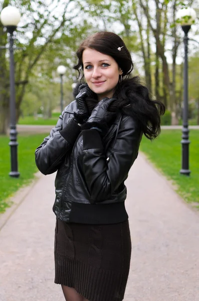 Menina atraente em uma jaqueta na estrada no parque — Fotografia de Stock