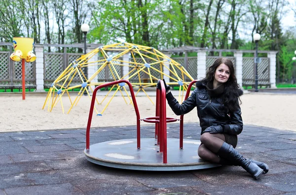Menina atraente em um casaco no parque infantil — Fotografia de Stock