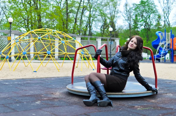 Привлекательная девушка в куртке на детской площадке — стоковое фото