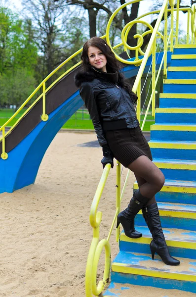 Attraktive Mädchen in einer Jacke auf dem Spielplatz — Stockfoto