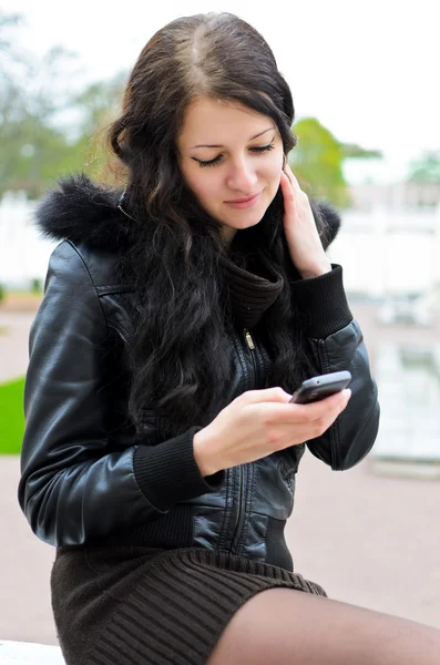 Aantrekkelijk meisje schrijven van een sms in park. — Stockfoto