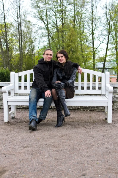 Portrét šťastnému páru na lavičce v parku. — Stock fotografie