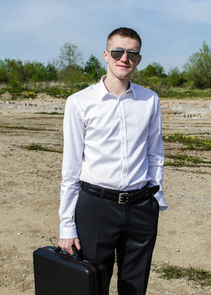 Empresario en gafas con una maleta en la mano —  Fotos de Stock