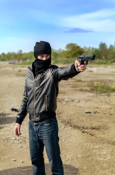Masked gunman taking aim with a gun — Stock Photo, Image