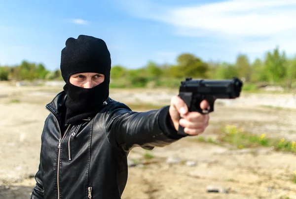 Pistoleiro mascarado apontando com uma arma — Fotografia de Stock