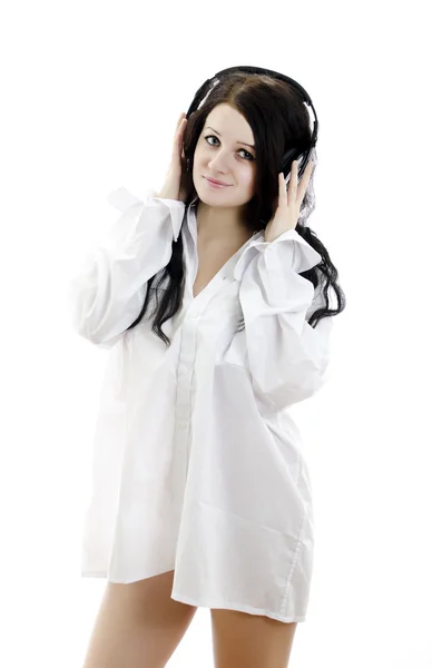 Sensual brunette girl in man's shirt with headphones. Isolated on whit — Stock Photo, Image