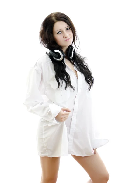 Sensual brunette girl in man's shirt with headphones. Isolated on whit — Stock Photo, Image