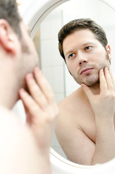 El hombre mira su barba y piensa en afeitarse —  Fotos de Stock