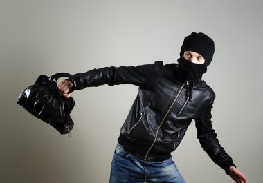 Portrait of running male burglar with a handbag.