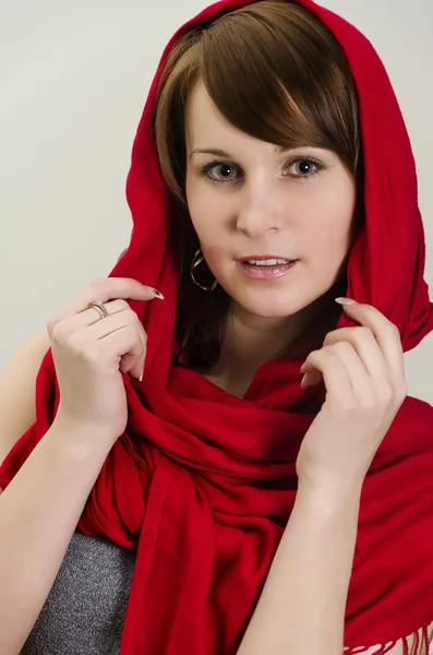 stock image Young woman in a red scarf. On grey background.