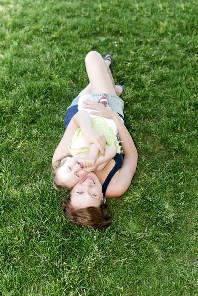 Glückliche Familie. Mutter und Tochter liegen im Gras. — Stockfoto