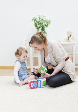 Mother and daughter playing in the children's cubes clipart