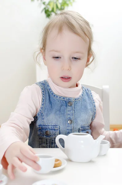 Cute little girl drinks tea with bagel — Stock Photo, Image
