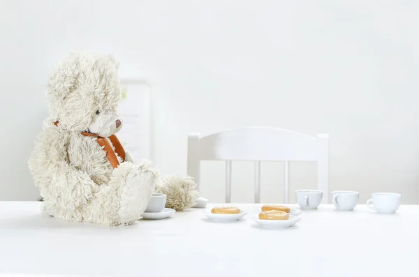 Тедди медведь пьет чай с бубликами за столом . — стоковое фото