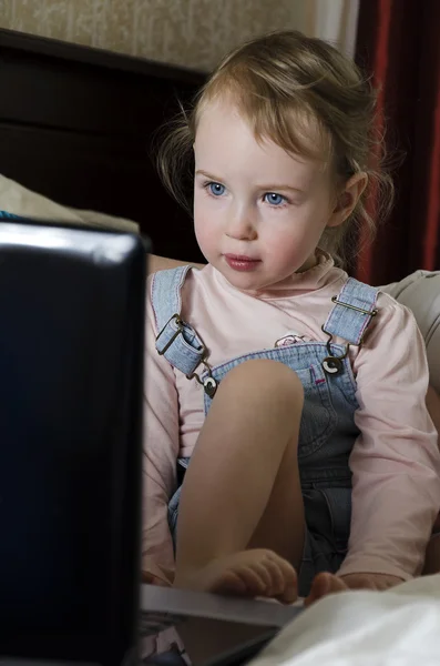 Petite fille regarde dessin animé sur l'ordinateur portable — Photo
