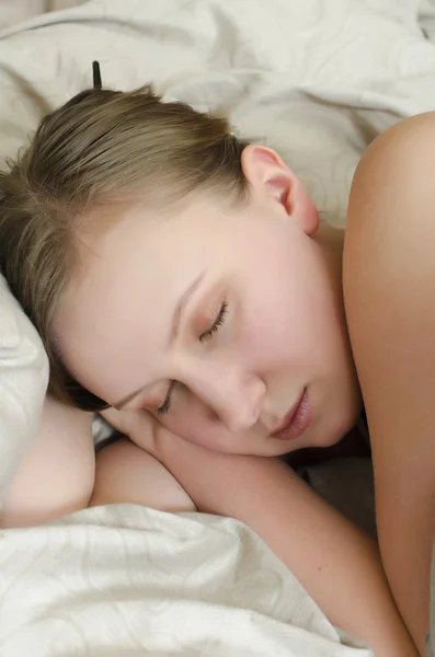 Fiatal lány alszik az ágyon, a takaró alatt — Stock Fotó