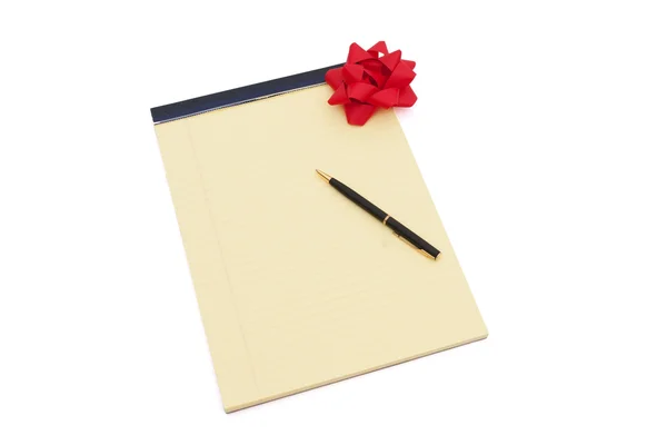 Blocco note bianco foderato di giallo con copia-spazio, fiocco rosso e una penna — Foto Stock