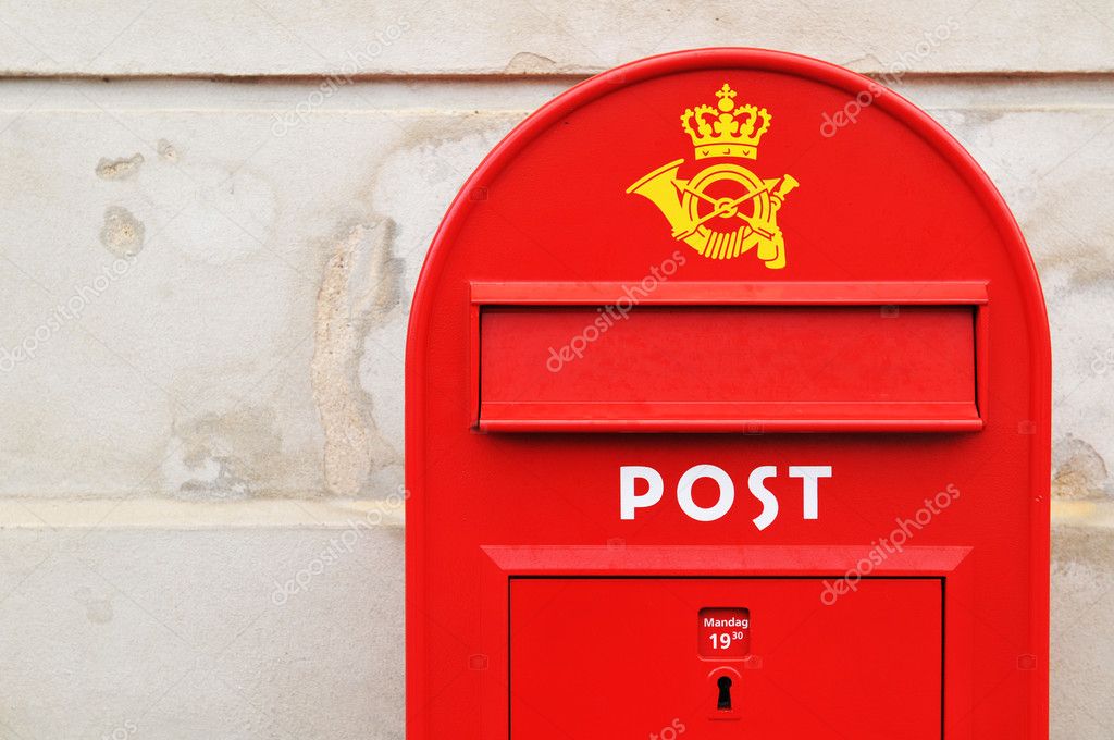 Red postal box against grunge wall in Copenhagen, Denmark