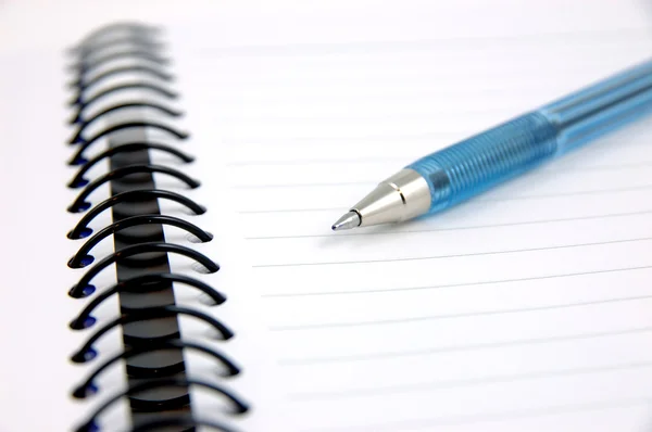 Blauwe pen op notitieboekje — Stockfoto
