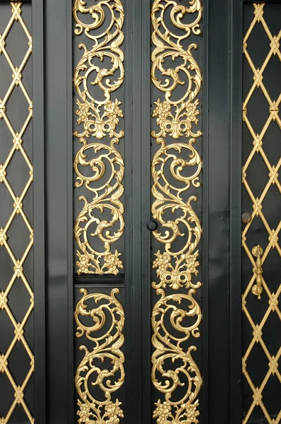 Черная дверь с золотым орнаментом — стоковое фото