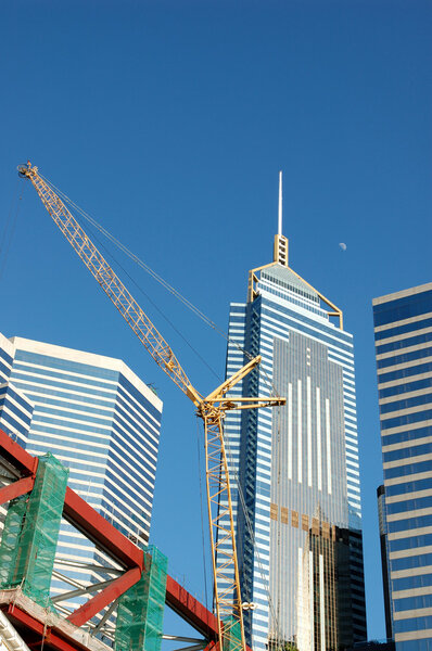 Construction crane and business buildings over blue sky