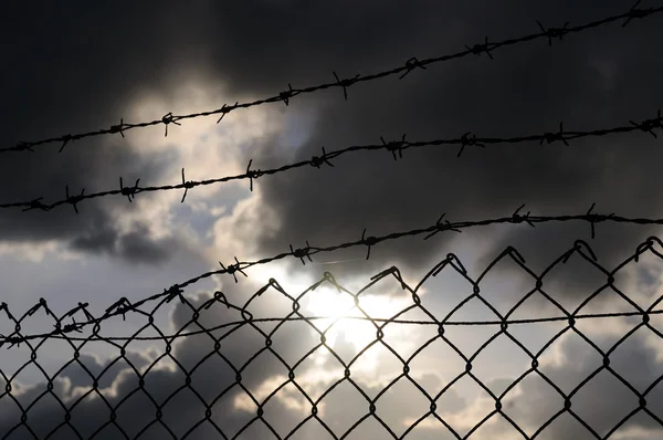 Wire staket över mörka moln — Stock fotografie