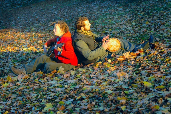 Couple of young musicians sitting in the ground — Stock Photo, Image