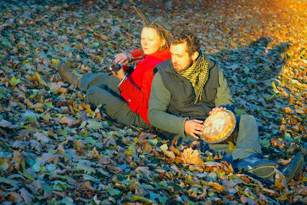 Couple of young musicians sitting in the ground — Stock Photo, Image