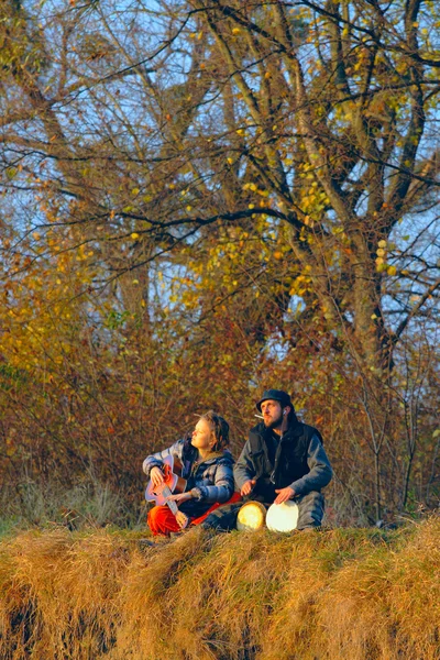 Пара молодих музикантів, що сидять на землі — стокове фото