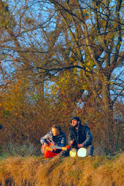 Coppia di giovani musicisti seduti sotto terra — Foto Stock