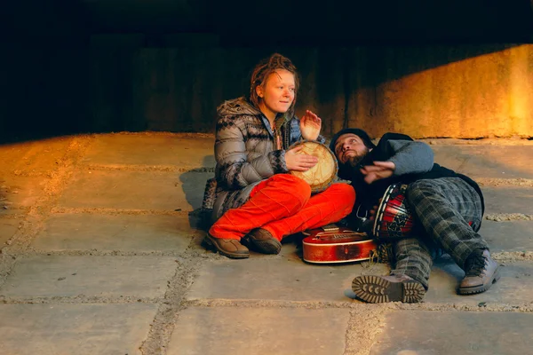 Пара молодых музыкантов, сидящих на земле — стоковое фото