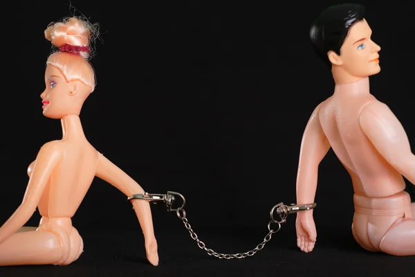Игрушечные мужчины и женщины, объединенные металлическими наручниками — стоковое фото