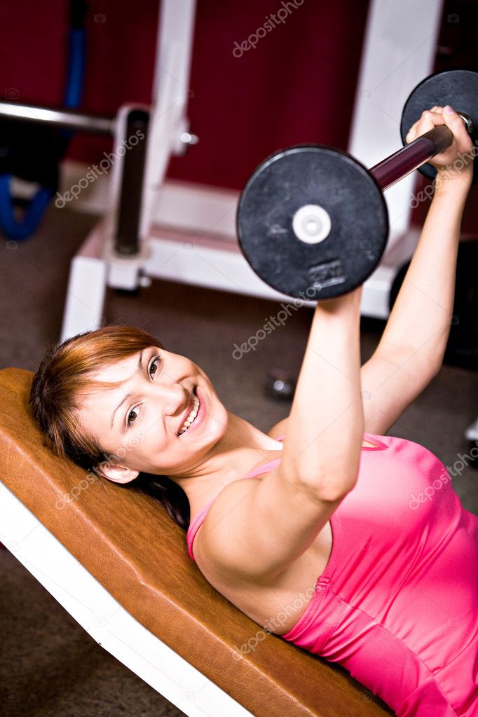 Free Photo | Young beautiful woman doing exercise with bar in a gym.  athletic girl doing workout in a fitness center. on a dark background the  gym. dressed in sport clothes.
