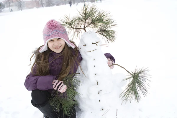 Happy girl with her snowman — Stock Photo, Image
