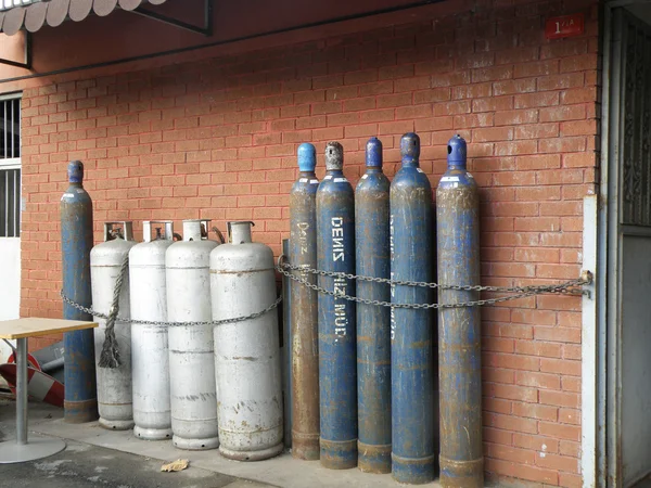 stock image Smaller and Bigger Gas Bottles in front of a Wall