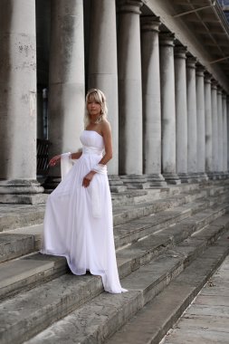 Young beautiful blonde bride portrait standing on a staircase of a classical building clipart